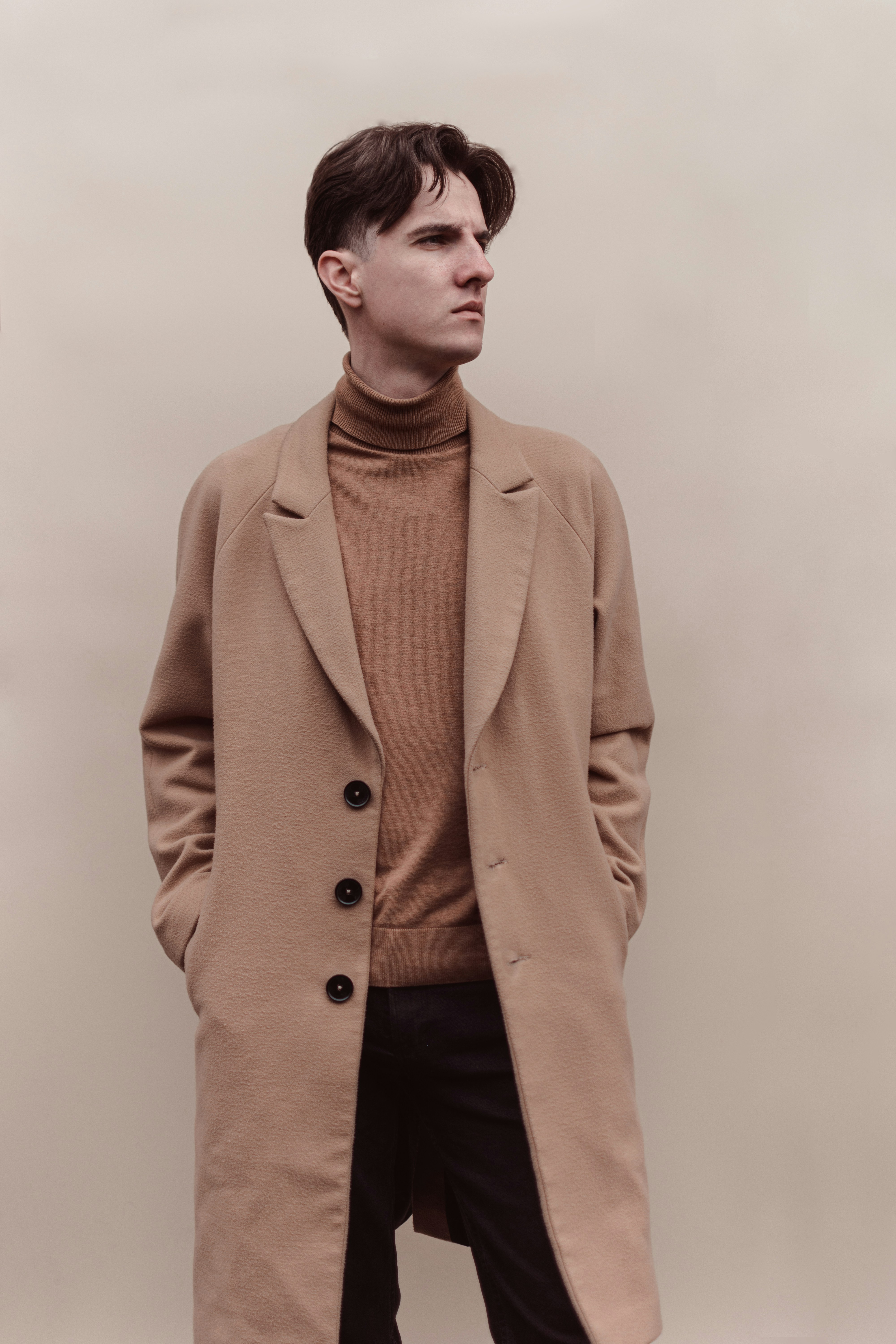 Man in a brown sweater under a brown coat.