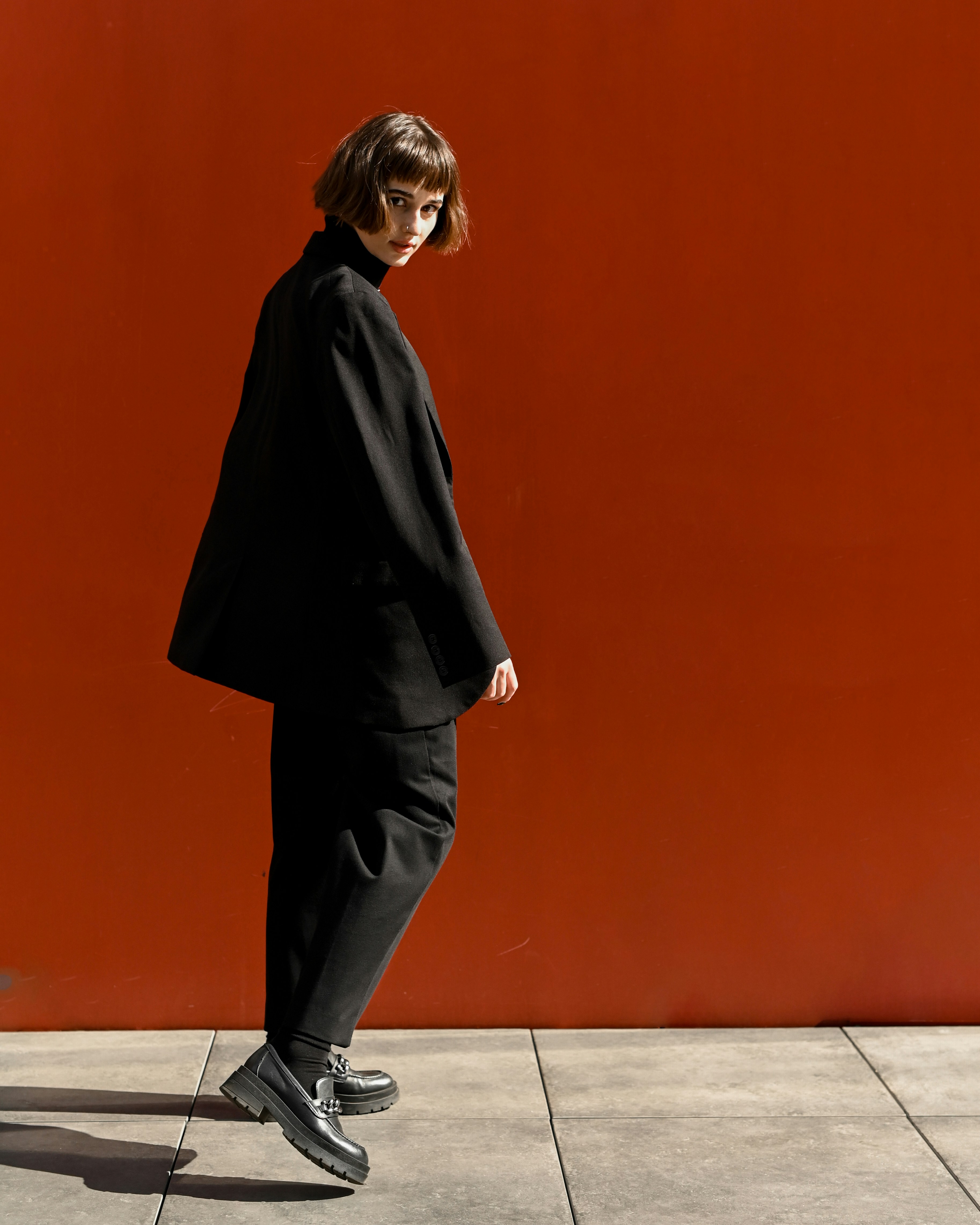 Woman in a black coat, black pants and black loafers.